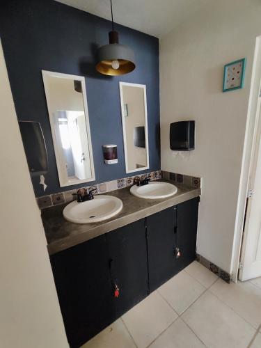 a bathroom with two sinks and two mirrors at Casa Aceves & Bueno Hotel Boutique in El Salto