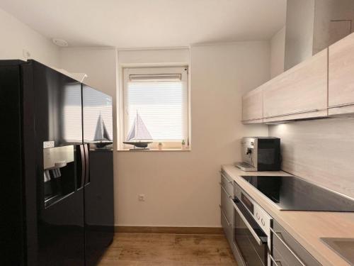 a kitchen with a black refrigerator and a window at Sonnenschein in Stevensweert