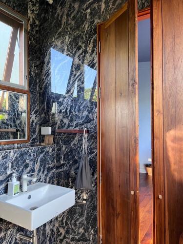 a bathroom with a white sink and a stone wall at Daraga ดารกะ in Chiang Dao