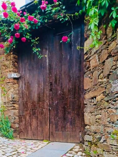 a wooden door with pink flowers on a stone wall at Escapada na Natureza - Charmoso Refúgio nas Alturas in Góis