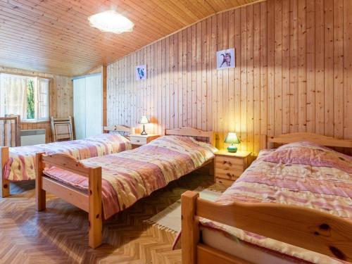 Dos camas en una habitación con paredes de madera. en Gîte au Calme avec Jardin, Proche Plages, 2 Chambres, Vélos et Randonnées à Machecoul - FR-1-306-805, en Machecoul