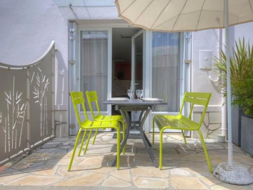 une terrasse avec des chaises jaunes, une table et un parasol dans l'établissement Gîte à proximité de la Loire avec Wi-Fi et équipement bébé - FR-1-306-814, à La Chapelle-Basse-Mer