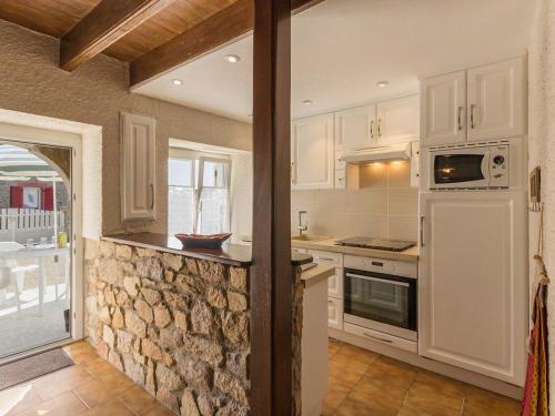 - une cuisine avec des placards blancs et un mur en pierre dans l'établissement Maison rénovée typique, calme, proche mer, 2 cours fermées, cheminée et équipements pour enfants. - FR-1-306-836, à Piriac-sur-Mer