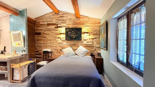 une chambre avec un lit et un mur en pierre dans l'établissement Ateliers créatifs, à Puyvert