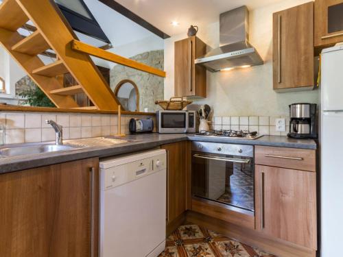 une cuisine avec des armoires en bois et un évier dans l'établissement Gîte familial rénové avec jardin, activités extérieures et recharge électrique à Mesquer - FR-1-306-843, à Mesquer