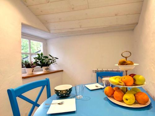 a blue table with a plate of fruit on it at Maison Authentique Bord de Rivière avec Jardin Privatif - Gîte de Pêche, Animaux sur Demande - FR-1-306-886 in Moisdon-la-Rivière