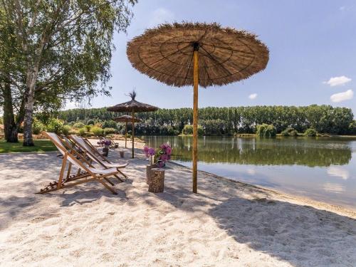 a beach with chairs and an umbrella on the sand at Villa Contemporaine avec Spa, Sauna, Piscine et Île Privative près de Nantes - FR-1-306-866 in Ligné