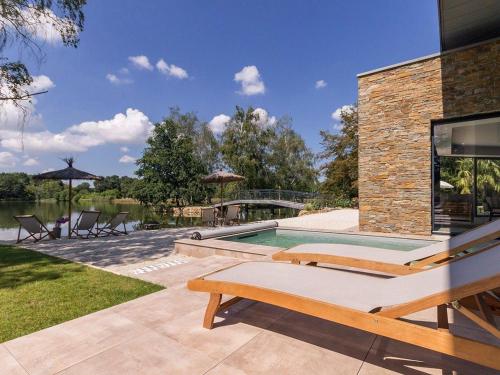 a backyard with a swimming pool and chairs and a house at Villa Contemporaine avec Spa, Sauna, Piscine et Île Privative près de Nantes - FR-1-306-866 in Ligné