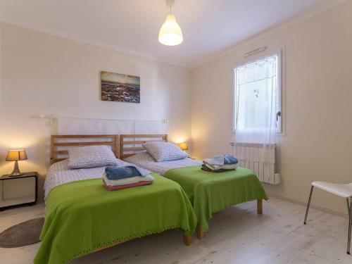 une chambre avec deux lits avec des draps verts et une fenêtre dans l'établissement Maison de charme à Pornic avec jardin, proche des plages et commerces, clim et wifi inclus - FR-1-306-1038, à Pornic