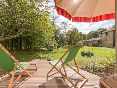 two lawn chairs sitting on a deck under an umbrella at Maison de Maître rénovée avec jardin, terrasse et équipements modernes, au calme de la campagne. - FR-1-306-928 in Saint-Père-en-Retz