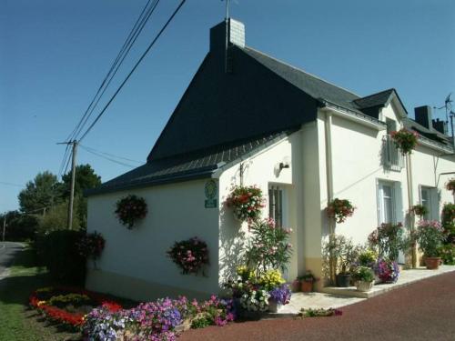 a white house with flowers in front of it at Location saisonnière: Gîte cosy avec jardin clos, proche plages et parc de Brière, wifi inclus! - FR-1-306-892 in Saint-André-des-Eaux