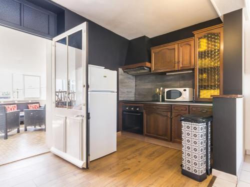 La cuisine est équipée d'un réfrigérateur blanc et de placards en bois. dans l'établissement Appartement Moderne avec Grande Terrasse, 3 Chambres, Proche Erdre et Canal de Nantes à Brest - FR-1-306-915, à Nort-sur-Erdre