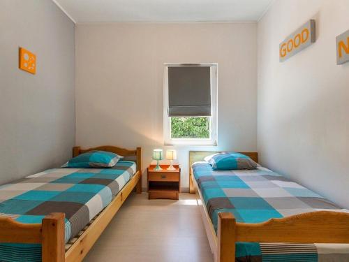 deux lits jumeaux dans une chambre avec fenêtre dans l'établissement Maison calme de campagne avec jardin clos, jeux pour enfants et vélos à proximité de Châteaubriant - FR-1-306-902, à Moisdon-la-Rivière