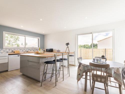 une cuisine avec une table et des chaises et une table et un comptoir dans l'établissement Gîte moderne avec confort, près de la mer, jardin clos, garage, WiFi, et équipements bébé - FR-1-306-1173, à Arthon-en-Retz