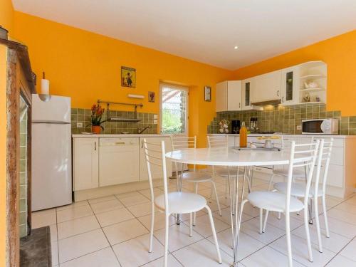 une cuisine avec des murs jaunes, une table blanche et des chaises dans l'établissement Gîte 2 chambres avec jardin privé, équipements bébé, internet, à 20 km de St Nazaire - FR-1-306-991, à Crossac