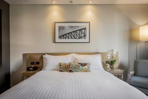 a bedroom with a large white bed with a blue chair at PARKROYAL Darling Harbour, Sydney in Sydney