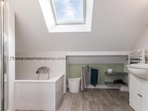 bagno con vasca, lavandino e lucernario. di "Charmante Écurie Rénovée, Proche Plages & Centre Ville, Jardin Privatif, Animaux Acceptés" - FR-1-306-1216 a Donges