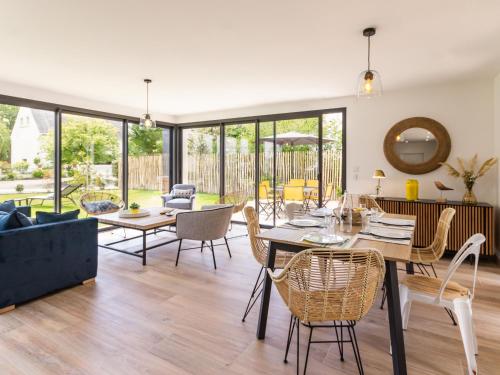 une salle à manger et un salon avec une table et des chaises dans l'établissement Maison moderne et lumineuse à 900m de la plage, jardin privé, terrasse, barbecue et 2 vélos adultes inclus. - FR-1-306-1204, à Mesquer