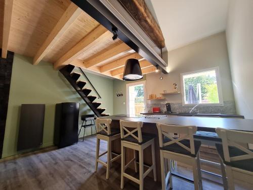 une cuisine avec un bar avec des chaises et un escalier dans l'établissement Studio cosy avec mezzanine, cour privative et espace vert à Rochetrejoux - FR-1-426-478, à Rochetrejoux