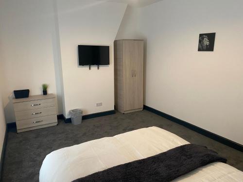 a bedroom with a bed and a tv on the wall at Houghton Guest House 1 in Stoke on Trent