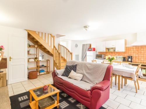 un salon avec une chaise rouge et une table dans l'établissement Gîte familial près de Guérande avec jardin, terrasse, jeux pour enfants, et coin détente - FR-1-306-1095, à Sainte-Reine-de-Bretagne