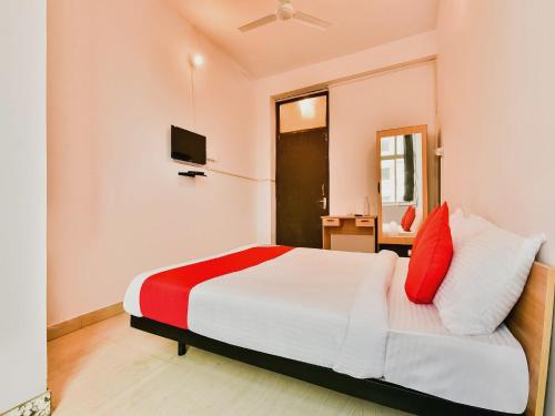 a bedroom with a bed with red and white pillows at Super Hotel O Capital Pearl in Patna