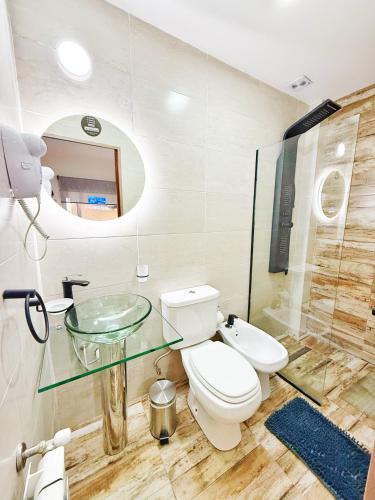 a bathroom with a toilet and a glass sink at Las Victorias Suites Bariloche in San Carlos de Bariloche