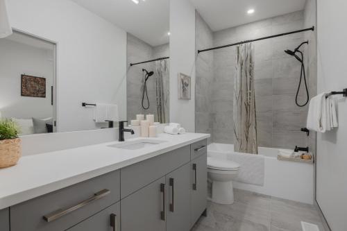 a white bathroom with a toilet and a shower at Upper and Lower, Great for Large Families, Fenced Yard in Calgary