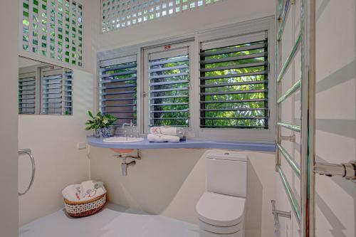 a bathroom with a toilet and a sink and windows at Sejala Beach Huts in Mission Beach