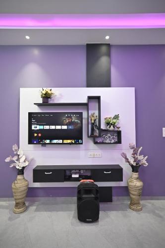 a tv in a purple wall with three vases at The Urban Escape in Trimbak