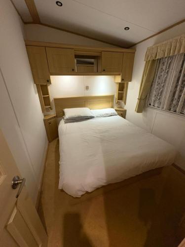 a small bedroom with a white bed in it at Gbk caravans in Rhyl