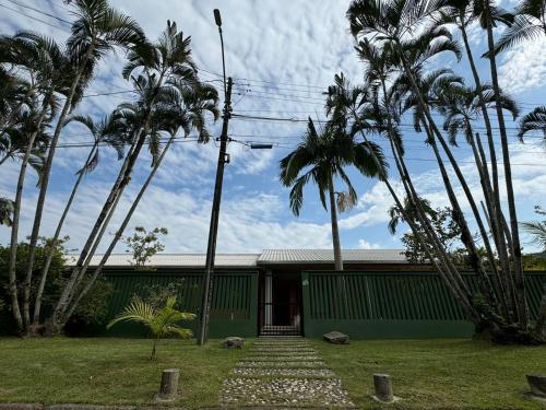 a green building with palm trees in front of it at Casa espetacular com 5 quartos 50 metros do mar in Matinhos