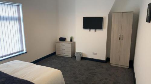 a bedroom with a bed and a tv on the wall at Houghton Guest House 2 in Stoke on Trent
