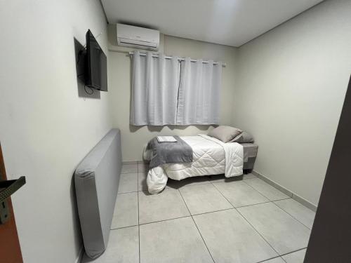 a small bedroom with a bed and a television at Apartamento próximo avenida da Semi Jóia in Limeira