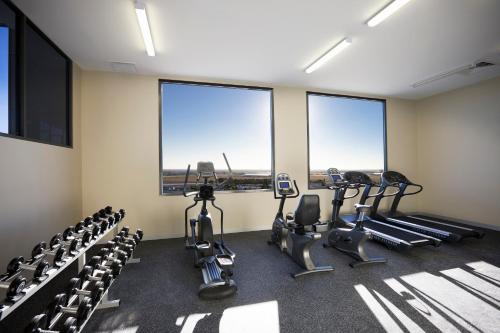 a gym with treadmills and elliptical machines and windows at Mantra Melbourne Airport in Melbourne