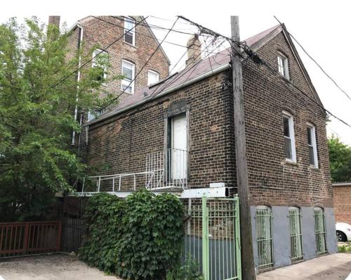 une maison en briques avec une clôture devant elle dans l'établissement Urban Coach Casa - Medical District- 10 to Downtown, à Chicago