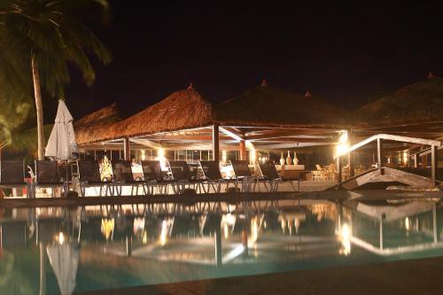 a resort with chairs and a pool at night at Serrambi Resort in Porto De Galinhas