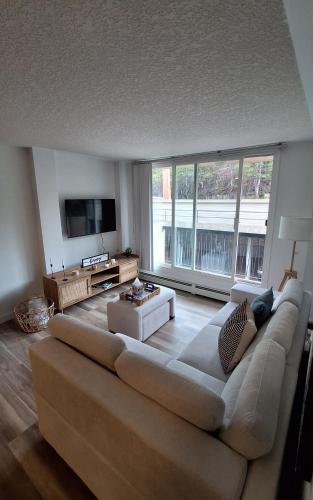 a living room with a large couch and a large window at Modern 1br Apt, Up to 4 people, Steps to 17th Ave, Downtown & Stampede in Calgary