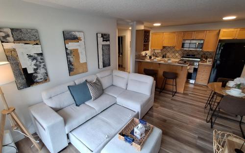 a living room with a white couch and a kitchen at Modern 1br Apt, Up to 4 people, Steps to 17th Ave, Downtown & Stampede in Calgary