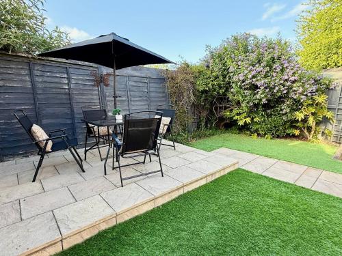 eine Terrasse mit Tisch, Stühlen und Sonnenschirm in der Unterkunft 15 Mins to Sizewell C - Driveway Parking - Contractor Friendly - 2 Bedroom in Saxmundham