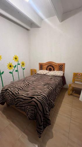 a bedroom with a bed with flowers on the wall at Posada Teyecac in San Juan Teotihuacán