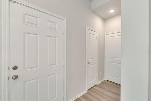 an empty hallway with white doors and wood floors at 4BR Spacious Family Retreat, 5min Lake Conroe, Large Backyard Grill in Montgomery