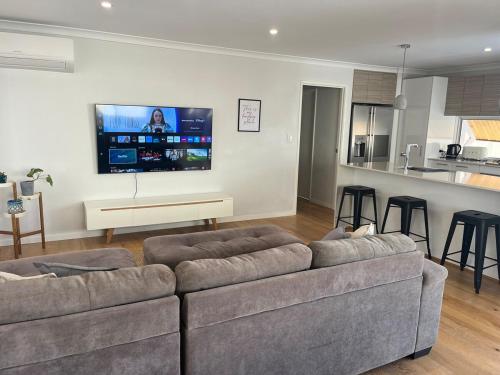 a living room with a couch and a tv on a wall at Coastal Retreat in Scarborough in Perth