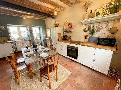 une cuisine avec une table et des chaises dans une pièce dans l'établissement Gîte XIXè de charme à Candes-St-Martin avec jardin clos - FR-1-381-612, à Candes-Saint-Martin
