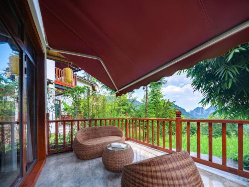a porch with wicker chairs and a table on a balcony at Zhangjiajie Ldyllic Pondside Timber Lodge in Zhangjiajie