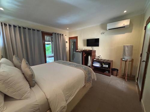 a bedroom with a large white bed and a television at Scallywags Beach Club in Gili Air