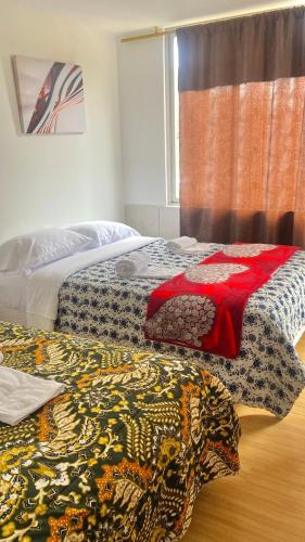 a room with two beds with colorful blankets on them at Casa Tomás hermosa e ideal para 7 personas in Baños