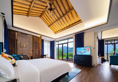 a bedroom with a large white bed and a flat screen tv at Zhangjiajie Ldyllic Pondside Timber Lodge in Zhangjiajie
