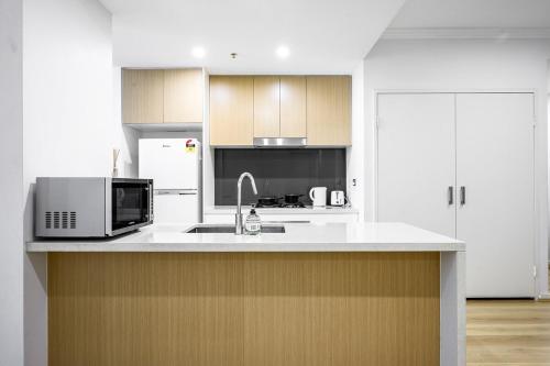 a white kitchen with a microwave and a sink at Liverpool 3Br Apt near Train Shop Hospital 8ppl in Liverpool