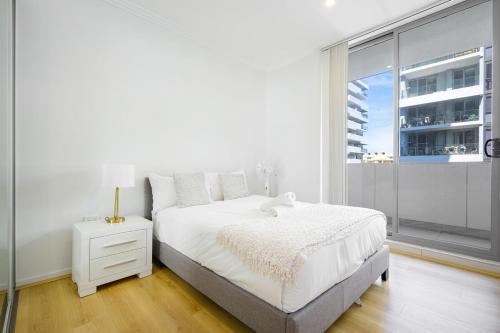a white bedroom with a bed and a window at Liverpool 3Br Apt near Train Shop Hospital 8ppl in Liverpool